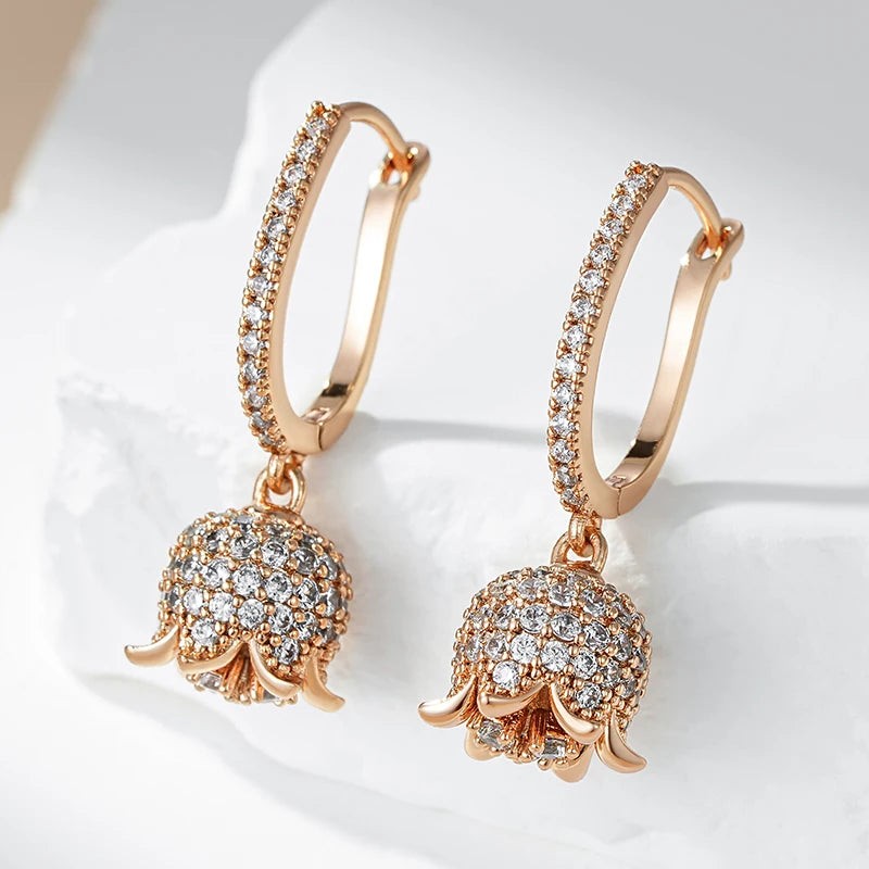 Rose gold bell flower earrings with pavé hoops resting on white stone