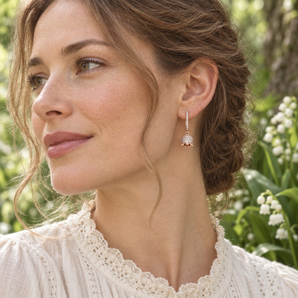 Woman in a lace-collar blouse wearing a rose gold lily of the valley earring in a spring garden
