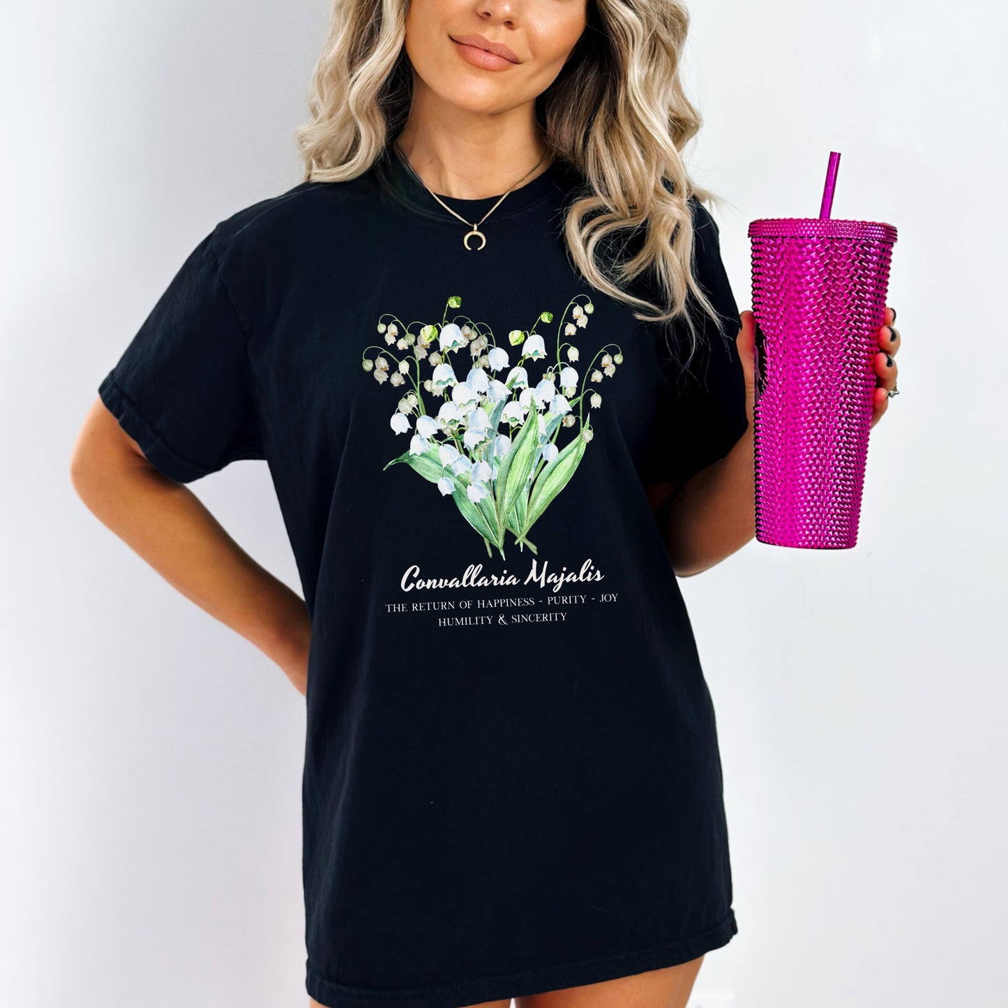 Woman wearing a black shirt with a floral and text design Comfort Colors garment-dyed Lily of the Valley May birth flower tee – Crossroads Dandelion