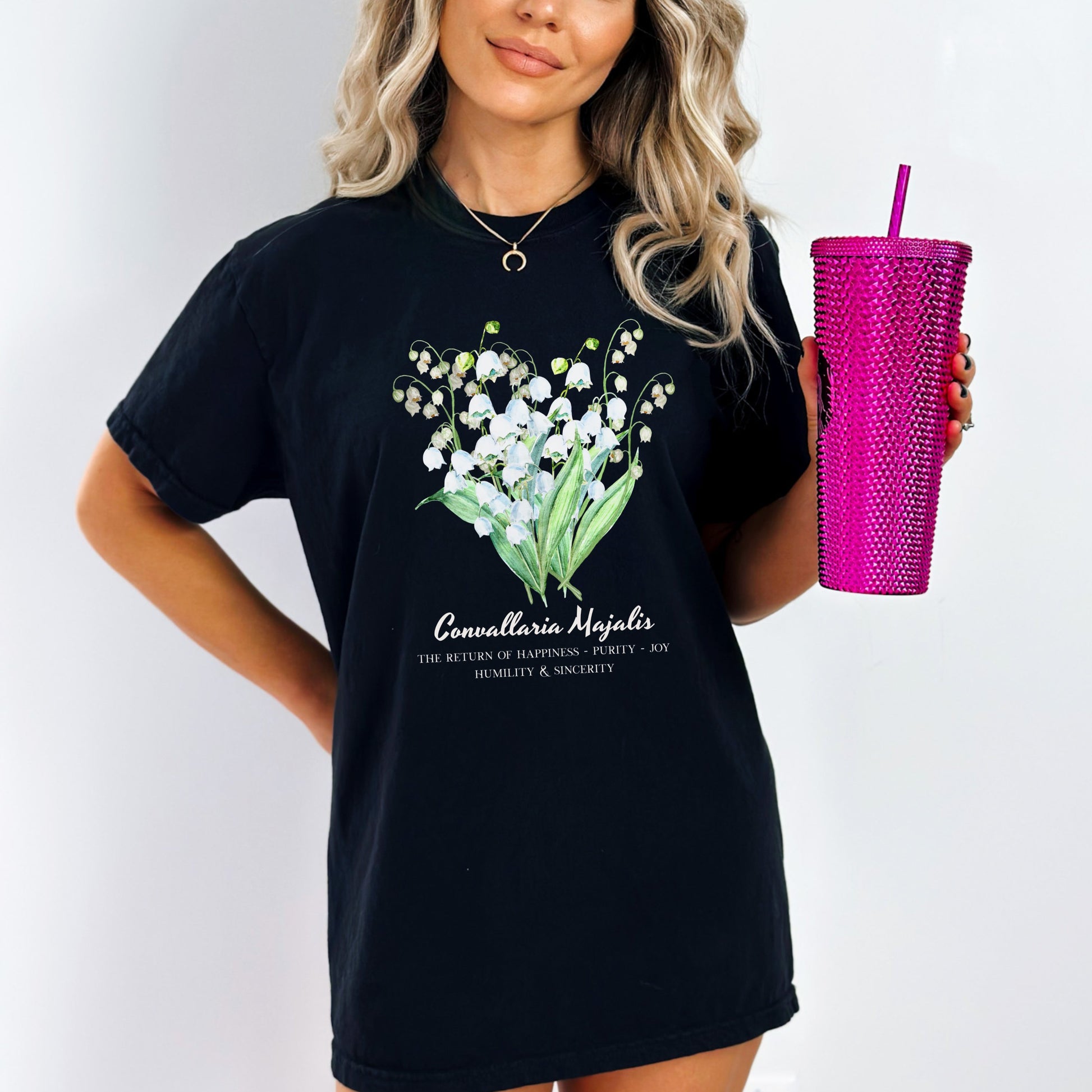 Woman wearing a black shirt with a floral and text design Comfort Colors garment-dyed Lily of the Valley May birth flower tee – Crossroads Dandelion