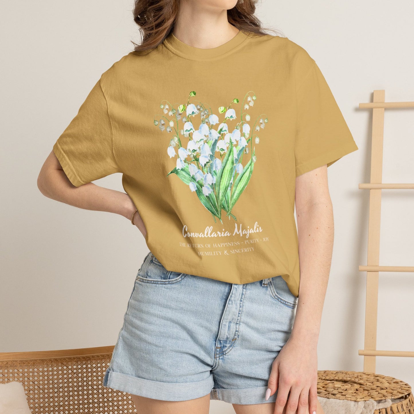 Woman wearing a Mustard Comfort Colors Lily of the Valley May birth month tee – Crossroads Dandelion