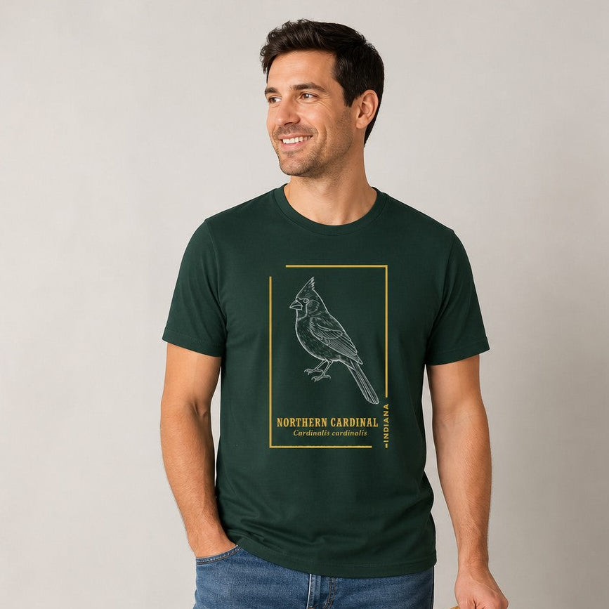Man in Bella Canvas 3001 forest green t-shirt featuring a vintage line art illustration of a Northern Cardinal framed in goldenrod and classic field guide typography, ideal for birdwatchers and wildlife art lovers, by Crossroads Dandelion