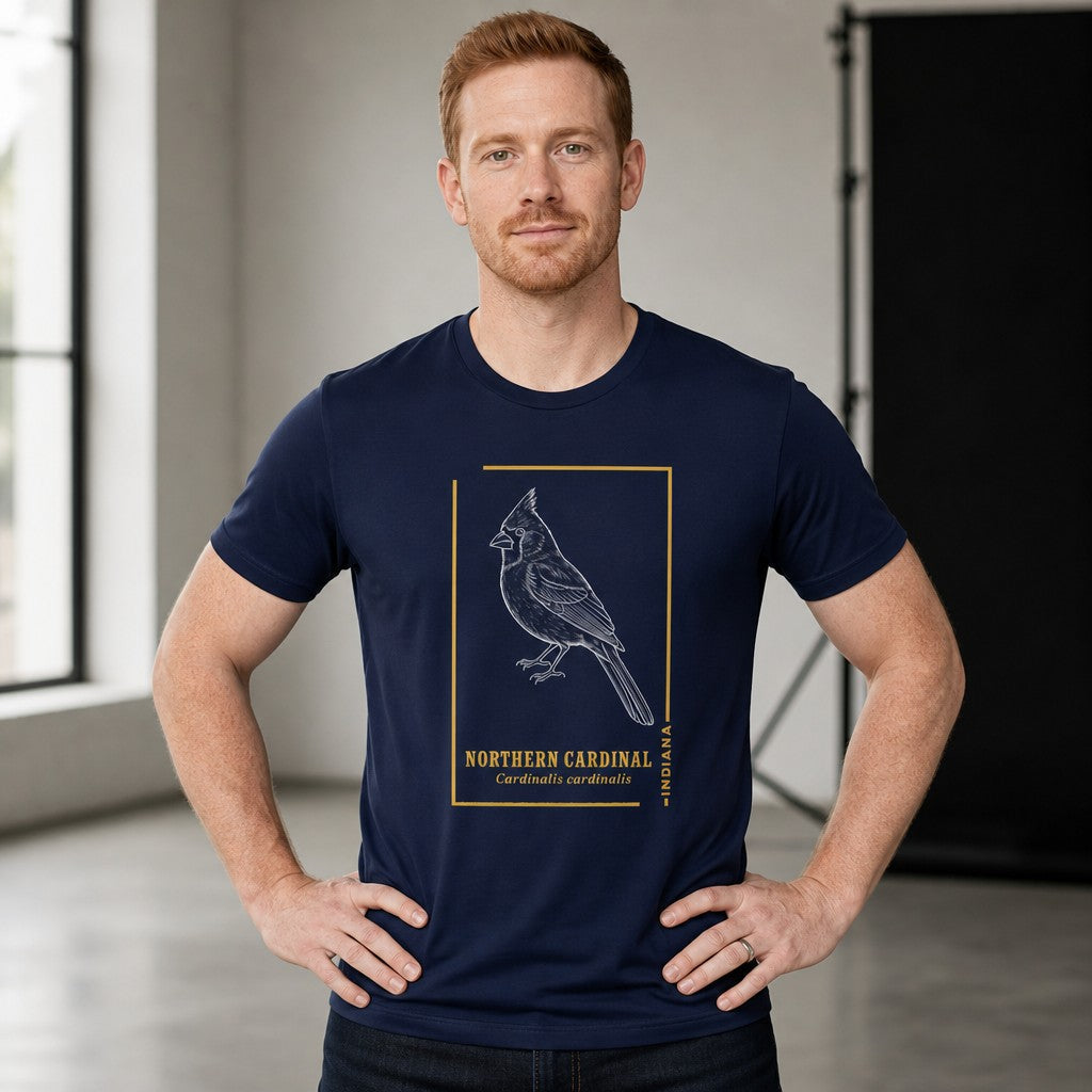 Man wearing a navy Bella Canvas 3001 t-shirt with a vintage-inspired line art northern cardinal illustration, goldenrod frame, and classic field guide typography, in a bright studio setting, ideal for birdwatchers, wildlife art lovers, and men who appreciate timeless minimalist nature designs, by Crossroads Dandelion