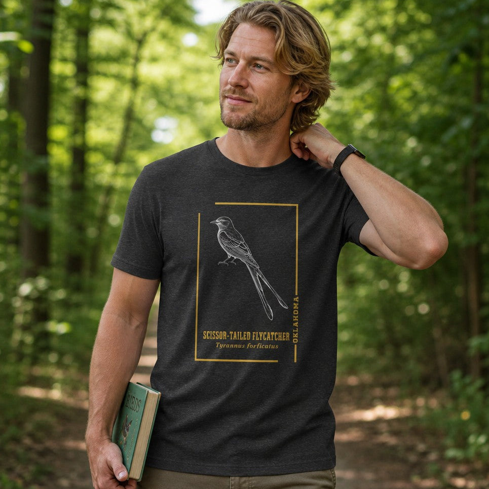 Man in dark grey heather Bella Canvas 3001 t-shirt featuring a vintage line art scissor-tailed flycatcher framed in gold, botanical naturalist bird design, forest walk setting, perfect for bird lovers and nature enthusiasts, by Crossroads Dandelion