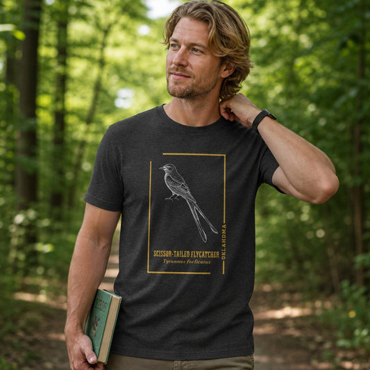Man in dark grey heather Bella Canvas 3001 t-shirt featuring a vintage line art scissor-tailed flycatcher framed in gold, botanical naturalist bird design, forest walk setting, perfect for bird lovers and nature enthusiasts, by Crossroads Dandelion