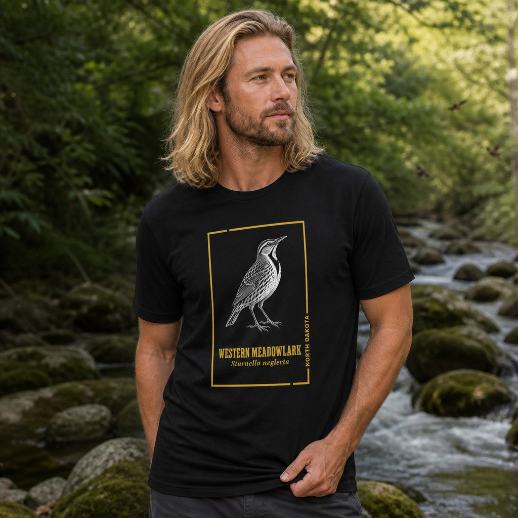 Man wearing a black Bella Canvas 3001 t-shirt with intricate line art of a Western Meadowlark framed in gold, featuring vintage scientific labeling, standing by a creek in a forest, heritage-inspired design for birdwatchers and nature lovers, by Crossroads Dandelion
