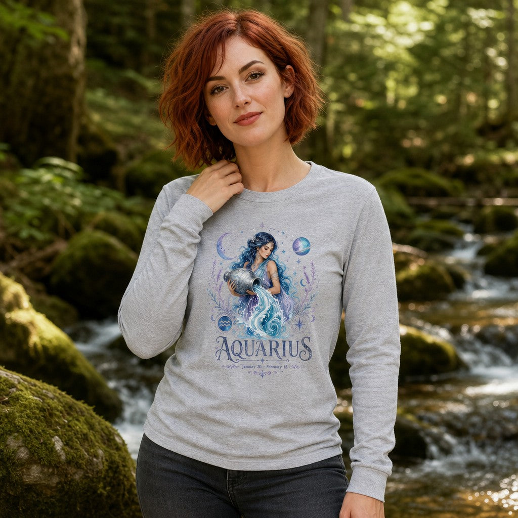 Woman with red hair wearing an athletic heather Bella Canvas 3501 long sleeve shirt featuring a watercolor Aquarius goddess design surrounded by celestial and botanical motifs, vintage garden and zodiac aesthetic, standing in a forest, for women and astrology lovers, by Crossroads Dandelion