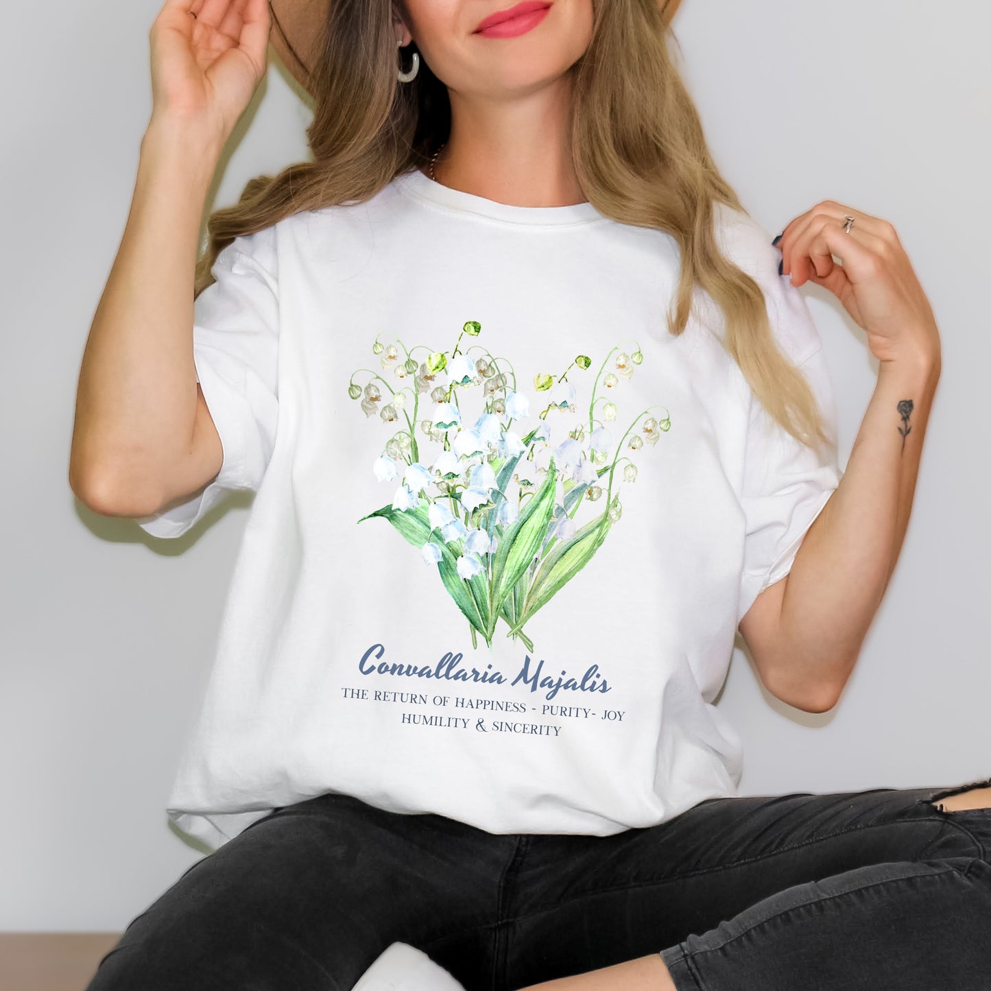 Woman wearing a White May birthday gift shirt with Lily of the Valley floral graphic – Crossroads Dandelion
