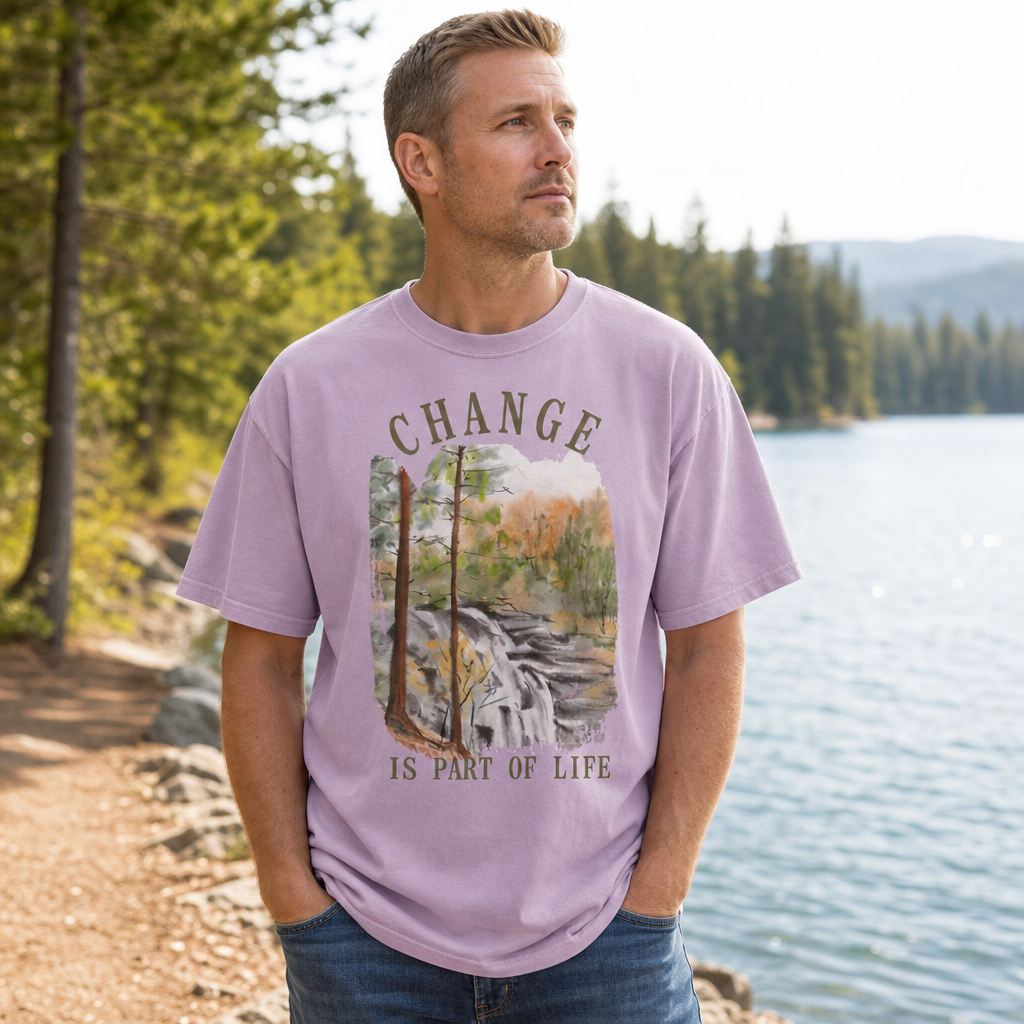 Man wearing an orchid Comfort Colors t-shirt with a nature graphic and text by a lake, by Crossroads Dandelion