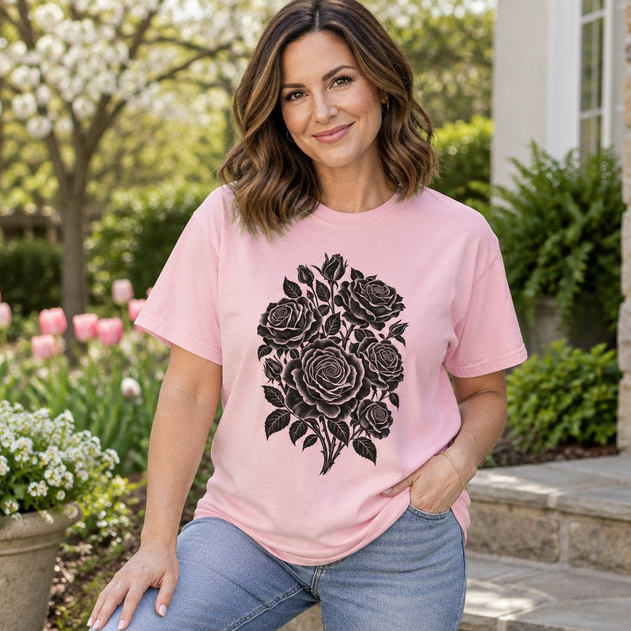 Woman wearing a blossom pink Comfort Colors® 1717 t-shirt featuring a bold black papercut silhouette of a rose bouquet, minimalist botanical design, outdoor garden setting, perfect for gardeners and flower lovers, by Crossroads Dandelion