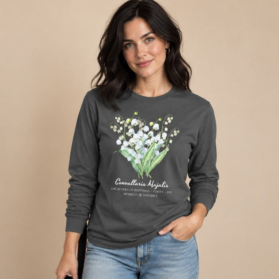 Woman in an asphalt Bella Canvas 3501 long sleeve shirt featuring a delicate watercolor lily of the valley botanical bouquet design, cottagecore vintage floral illustration for nature and garden lovers, by Crossroads Dandelion
