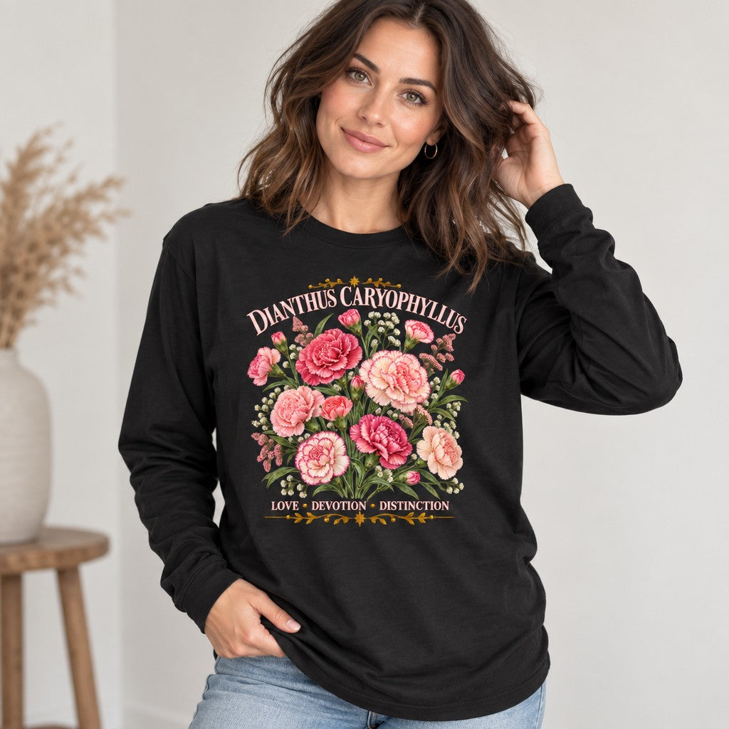 Woman in black Bella Canvas 3501 long sleeve featuring a vintage cottagecore watercolor illustration of pink and blush carnations with ruffled greenery, labeled 'DIANTHUS CARYOPHYLLUS' and symbolic words 'LOVE · DEVOTION · DISTINCTION', perfect for garden lovers or nostalgic botanical style, studio setting, by Crossroads Dandelion