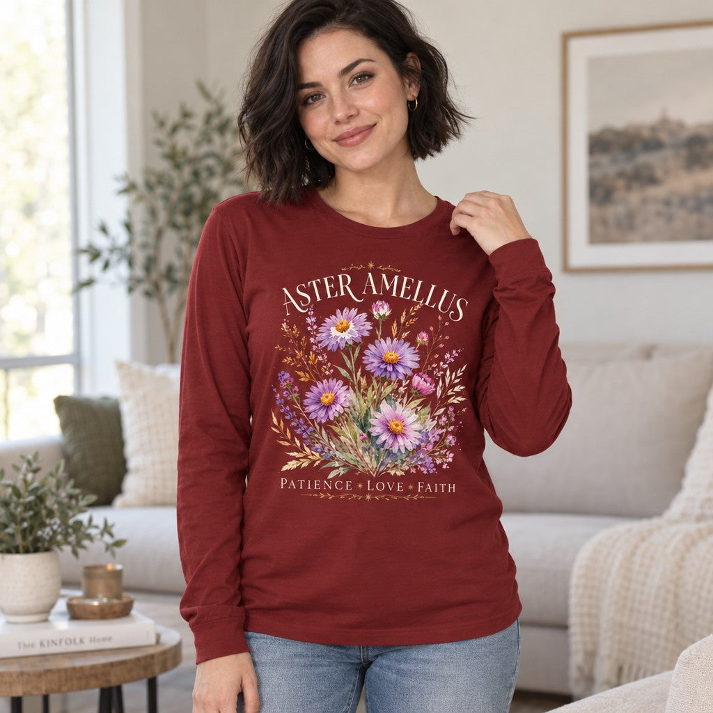 Woman wearing a cardinal Bella Canvas® 3501 long sleeve shirt featuring a vintage romantic botanical design of hand-painted aster and amellus flowers in lavender, pink, and violet with golden wheat accents, elegant cream serif text, in a cozy living room, for nature lovers and women who appreciate delicate floral apparel, by Crossroads Dandelion