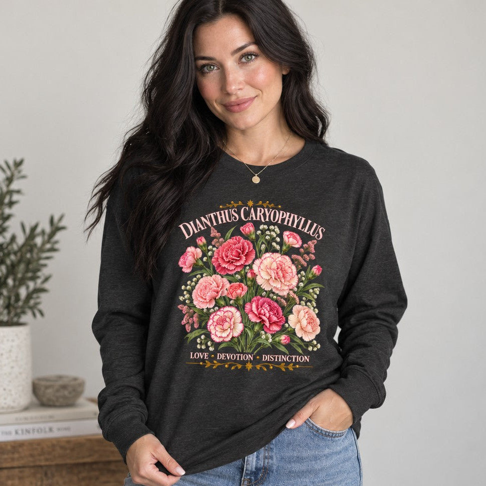 Woman in dark grey heather Bella Canvas 3501 long sleeve tee featuring a vintage watercolor illustration of pink and blush carnations with greenery and elegant serif text reading 'DIANTHUS CARYOPHYLLUS', nostalgic botanical plate, cottagecore style, perfect for garden lovers, by Crossroads Dandelion