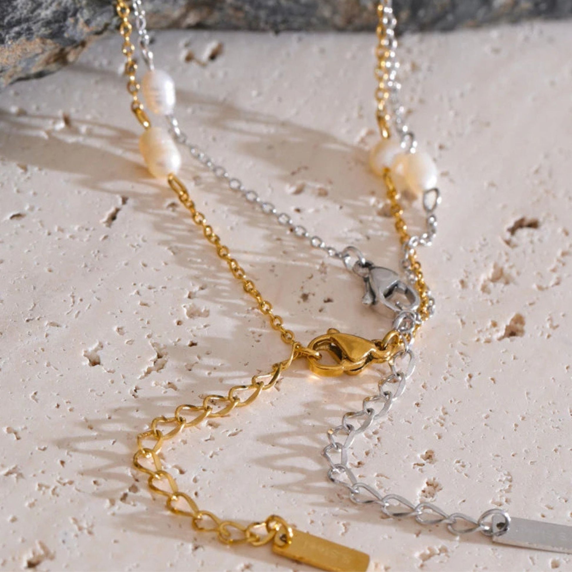 Gold and silver color chain necklace with  clasps view on a texture surface