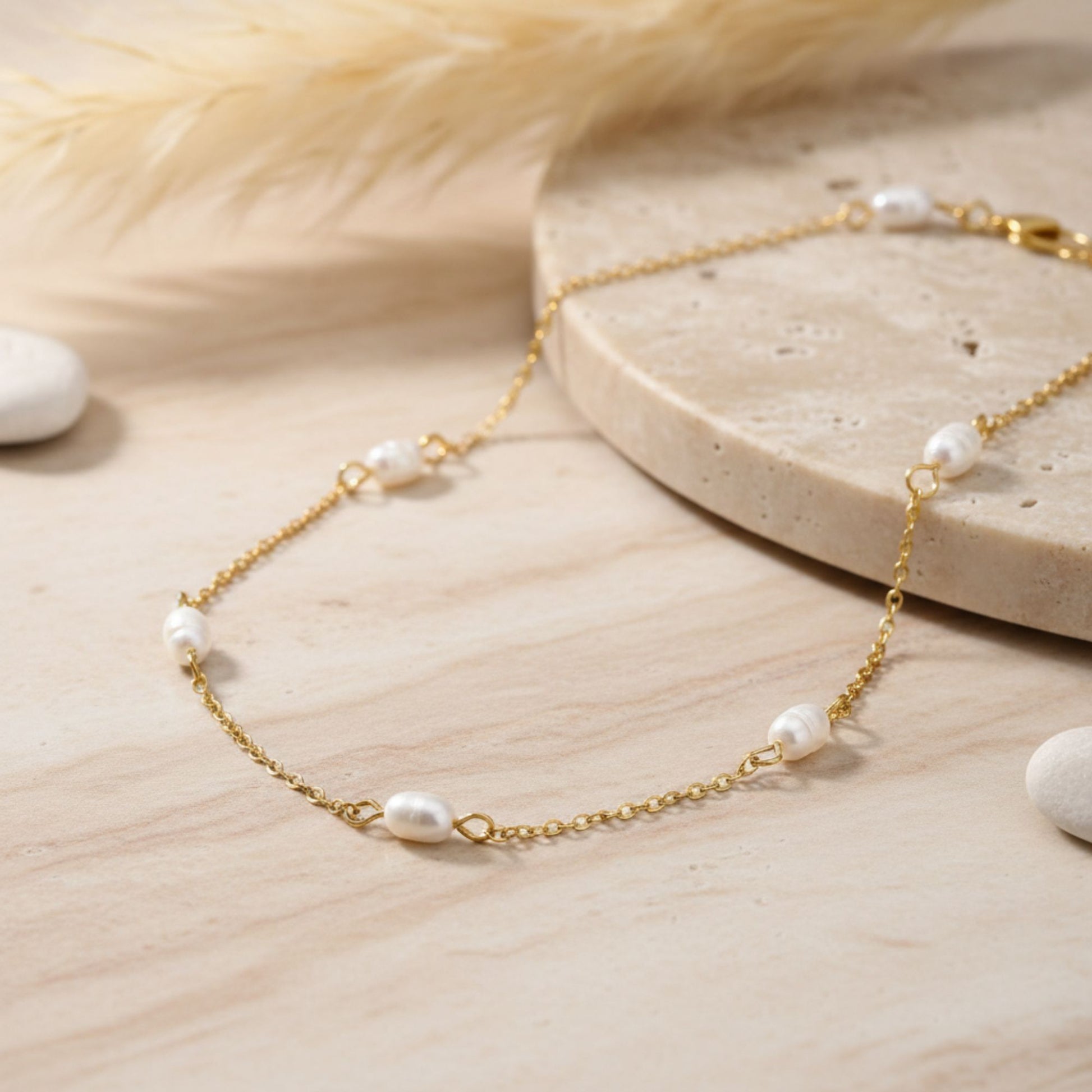 Gold plated station necklace with small pearls on a wooden surface