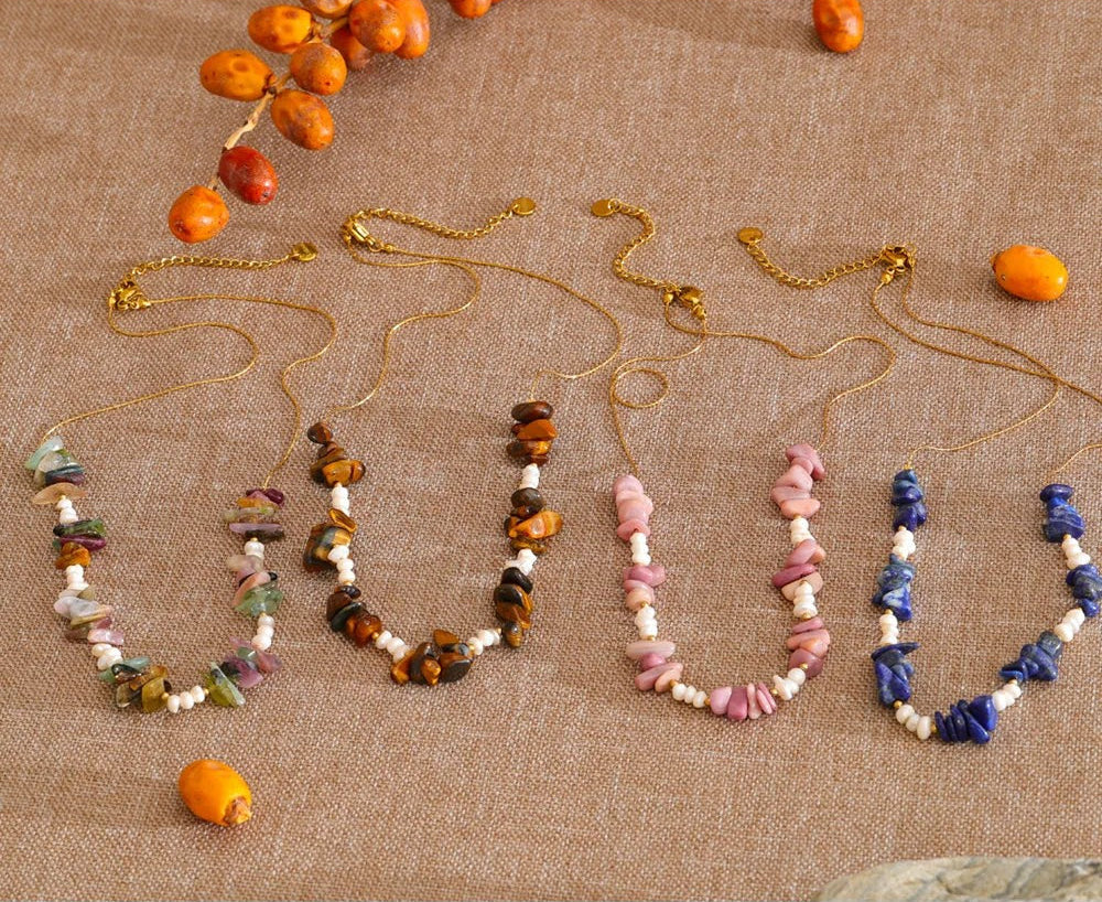 Four stone chip and pearl necklaces in mixed, tiger stone, pink and blue on natural linen