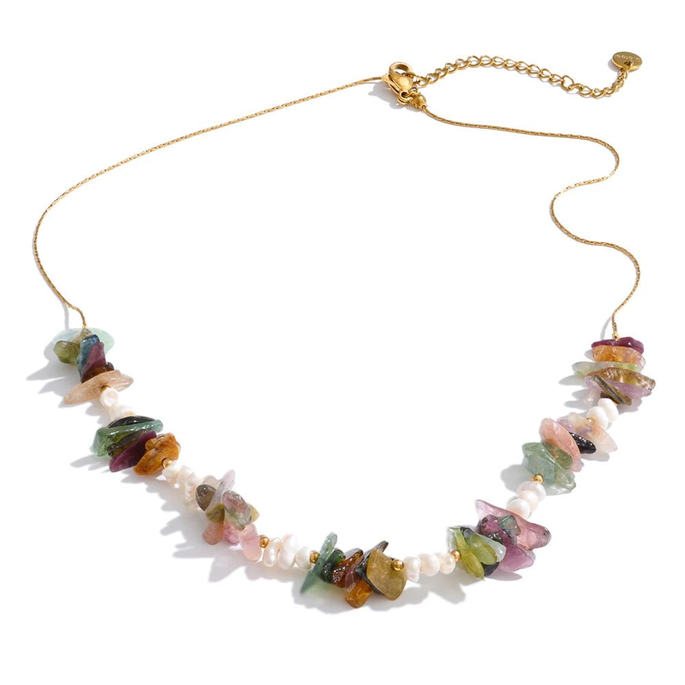 Mixed multicolor stone chip and pearl necklace on a gold-plated chain, laid flat on white