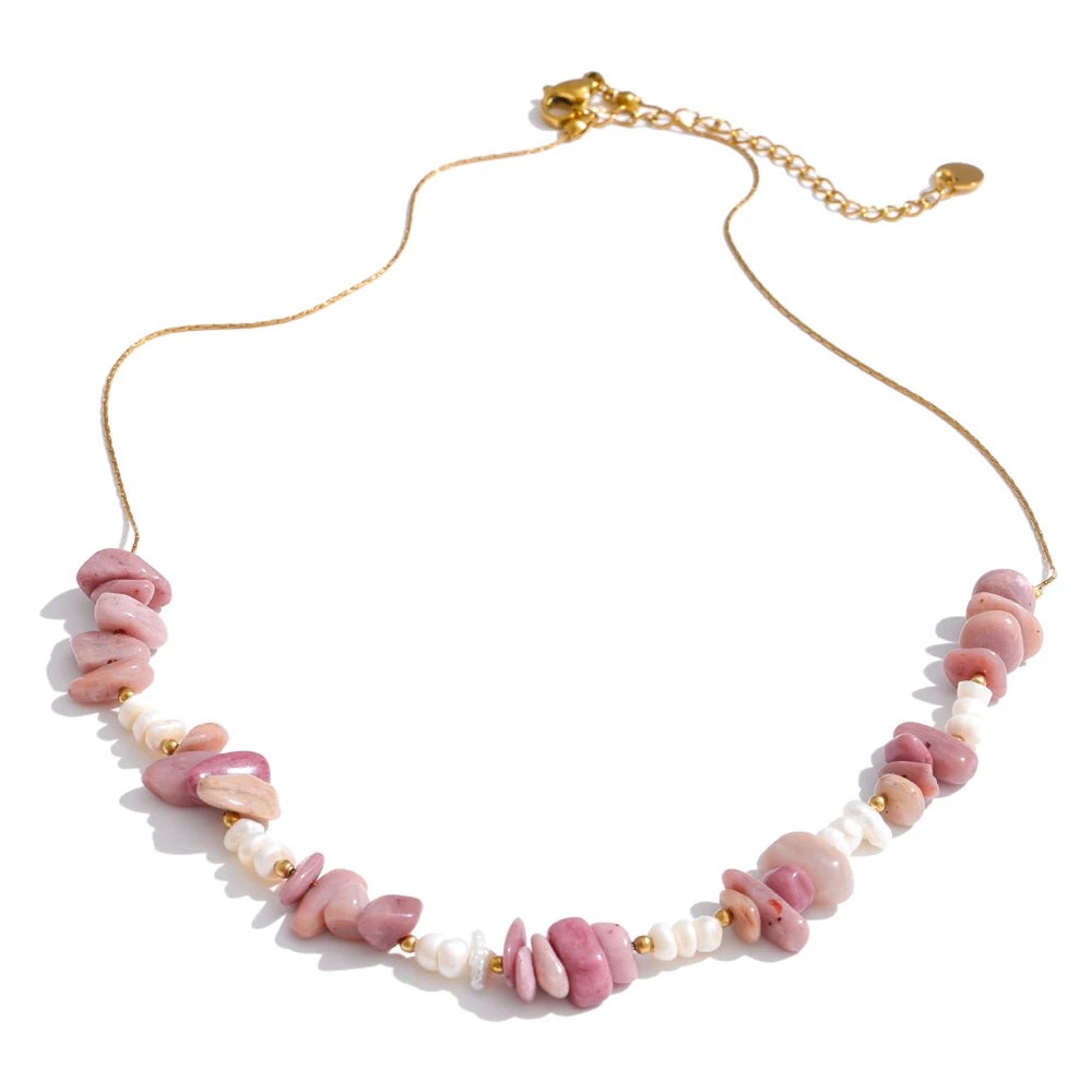 Pink rhodochrosite chip and pearl necklace on a gold-plated chain, laid flat on white
