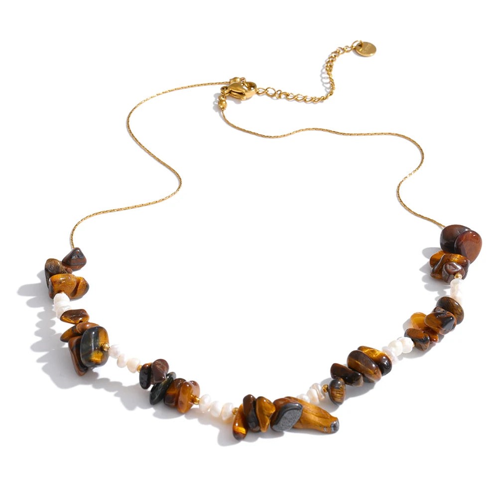 Tiger stone chip and pearl necklace on a gold-plated chain, laid flat on white