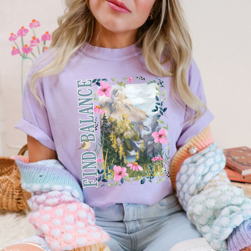 Woman is using a Comfort Colors inspirational  t-shirt  in Orchid color with relaxed lifestyle aesthetic, cute gift for nature enthusiasts, premium casual apparel styling, by Crossroads Dandelion
