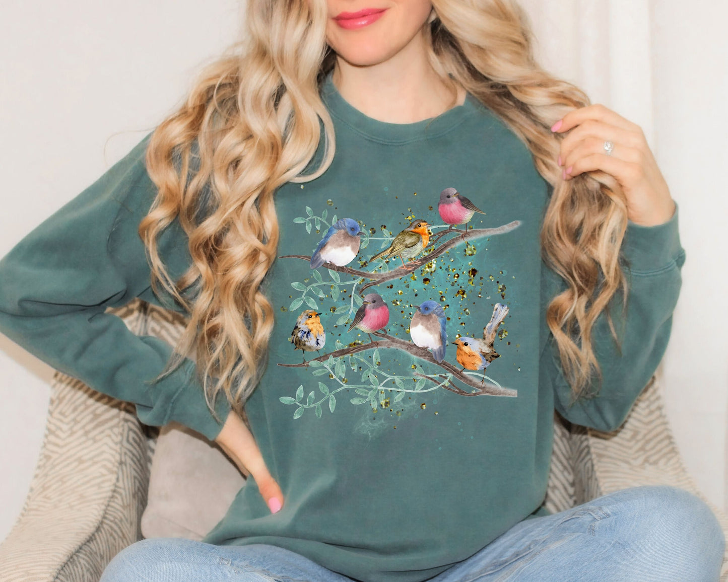 Blonde Woman using  a blue spruce color sweatshirt with a colorful 
bird design