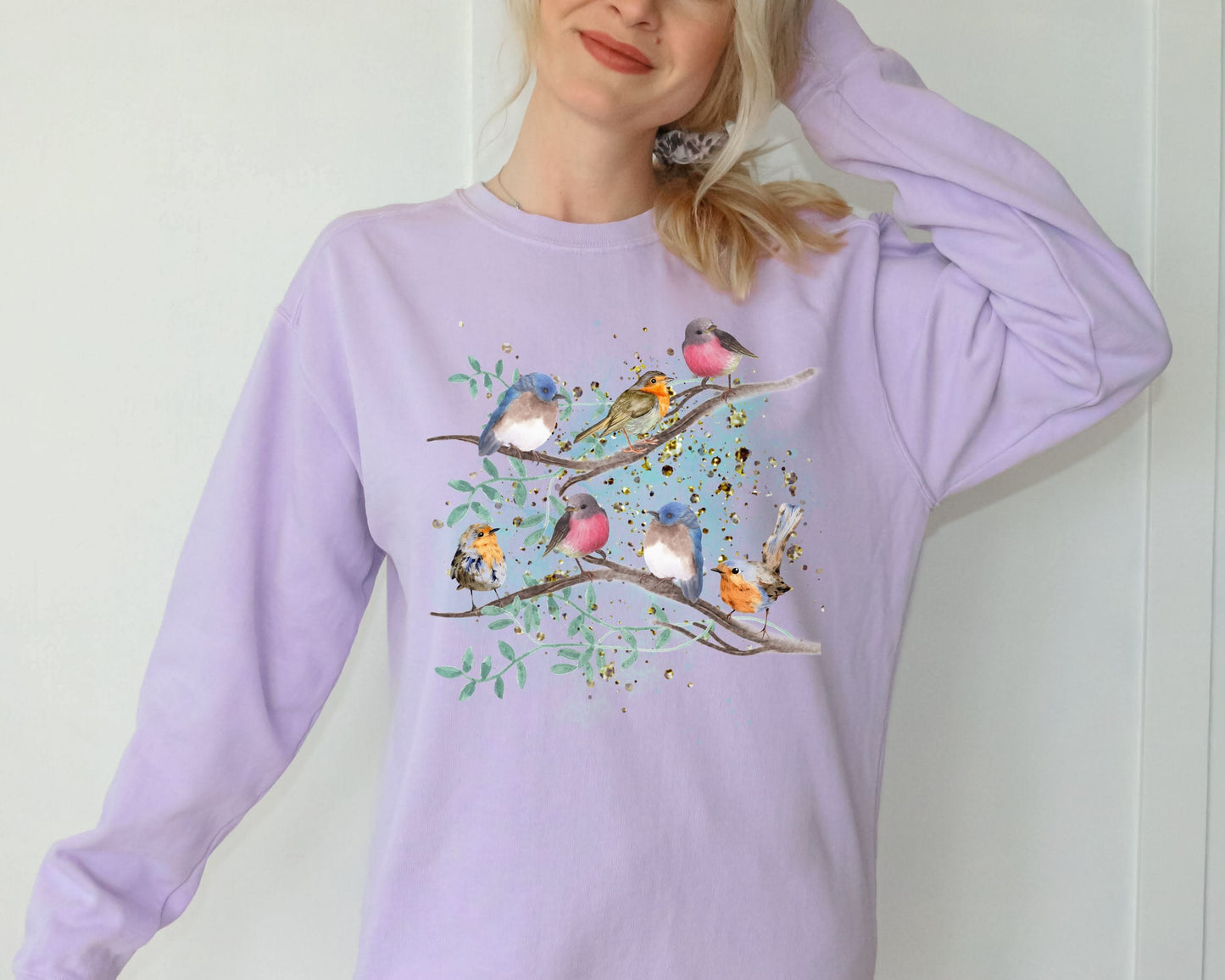 Woman wearing a light purple sweatshirt -orchid color- with a cute bird design on a plain background