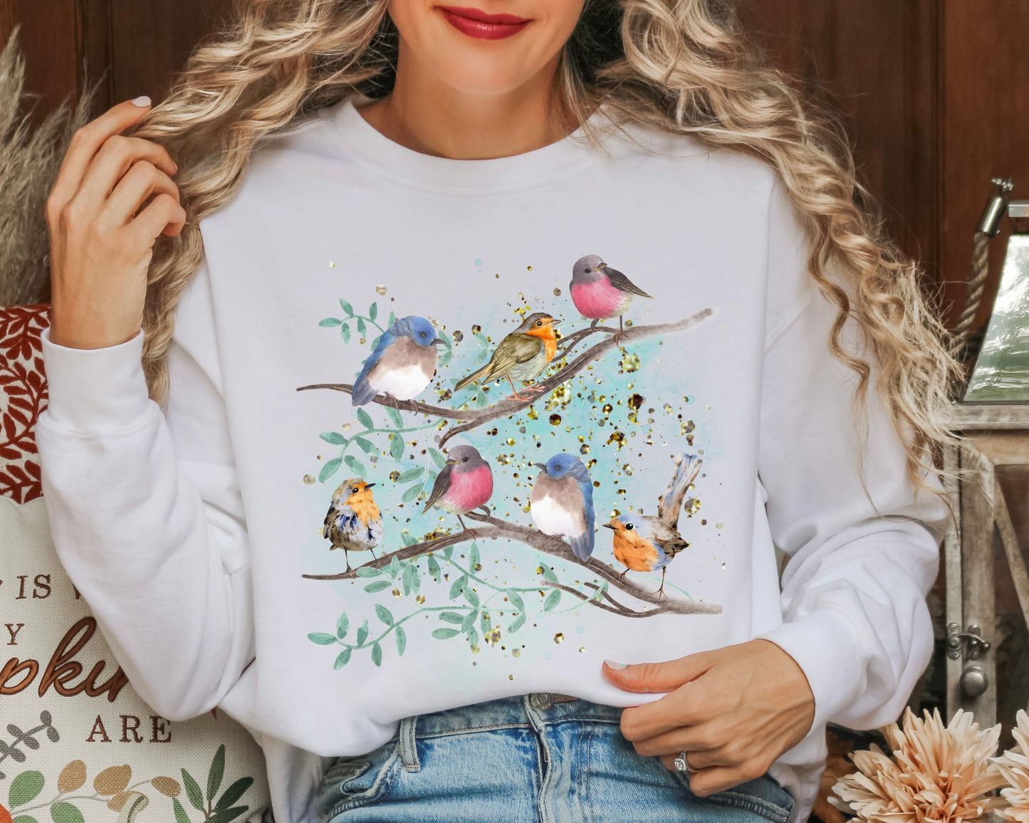 Woman wearing a white sweatshirt with colorful bird and branches design