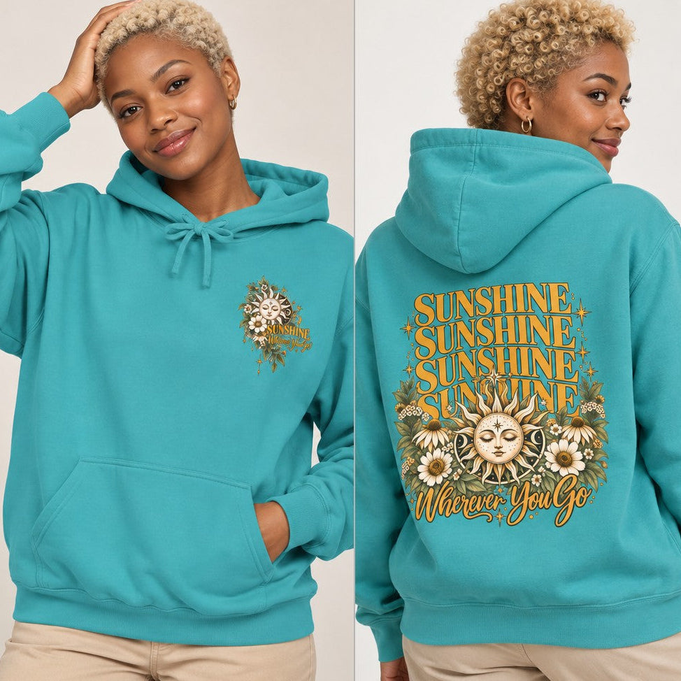 Woman wearing a seafoam hoodie with a retro boho-style 'Sunshine Wherever You Go' sunflower and sun face design, perfect for positive affirmation lovers, casual style, by Crossroads Dandelion