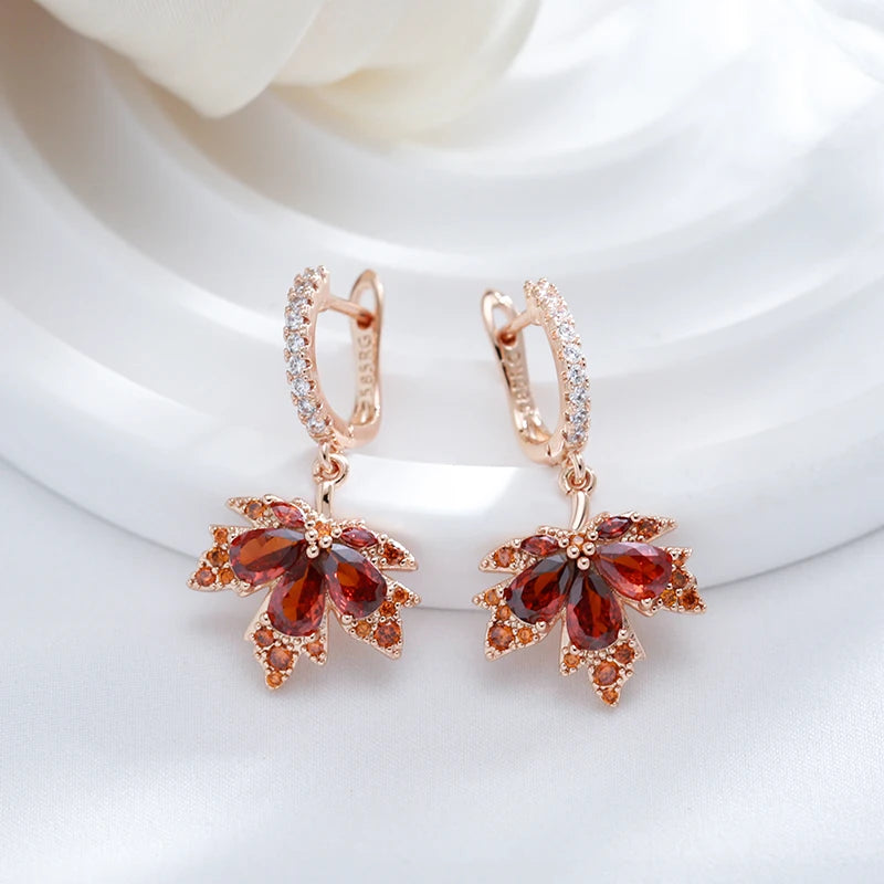 Rose gold maple earrings with red gemstones on a white background