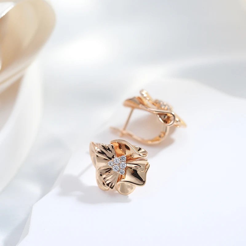 Ruffled flower earrings on white fabric, one showing the hinged English-lock closure