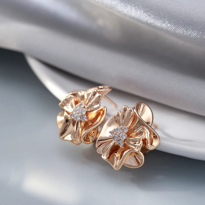 Rose gold ruffled flower earrings resting beside soft silver satin