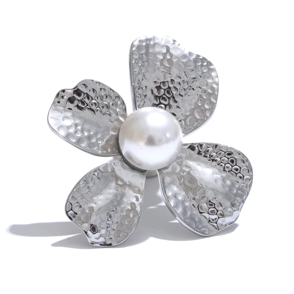 Silver flower-shaped brooch with a pearl center on a white background