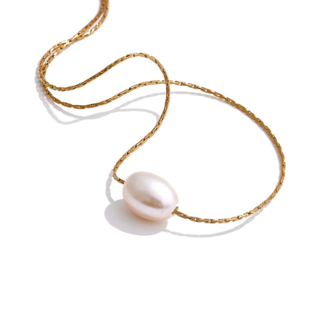 Single oval freshwater pearl on a fine gold chain necklace, laid on white