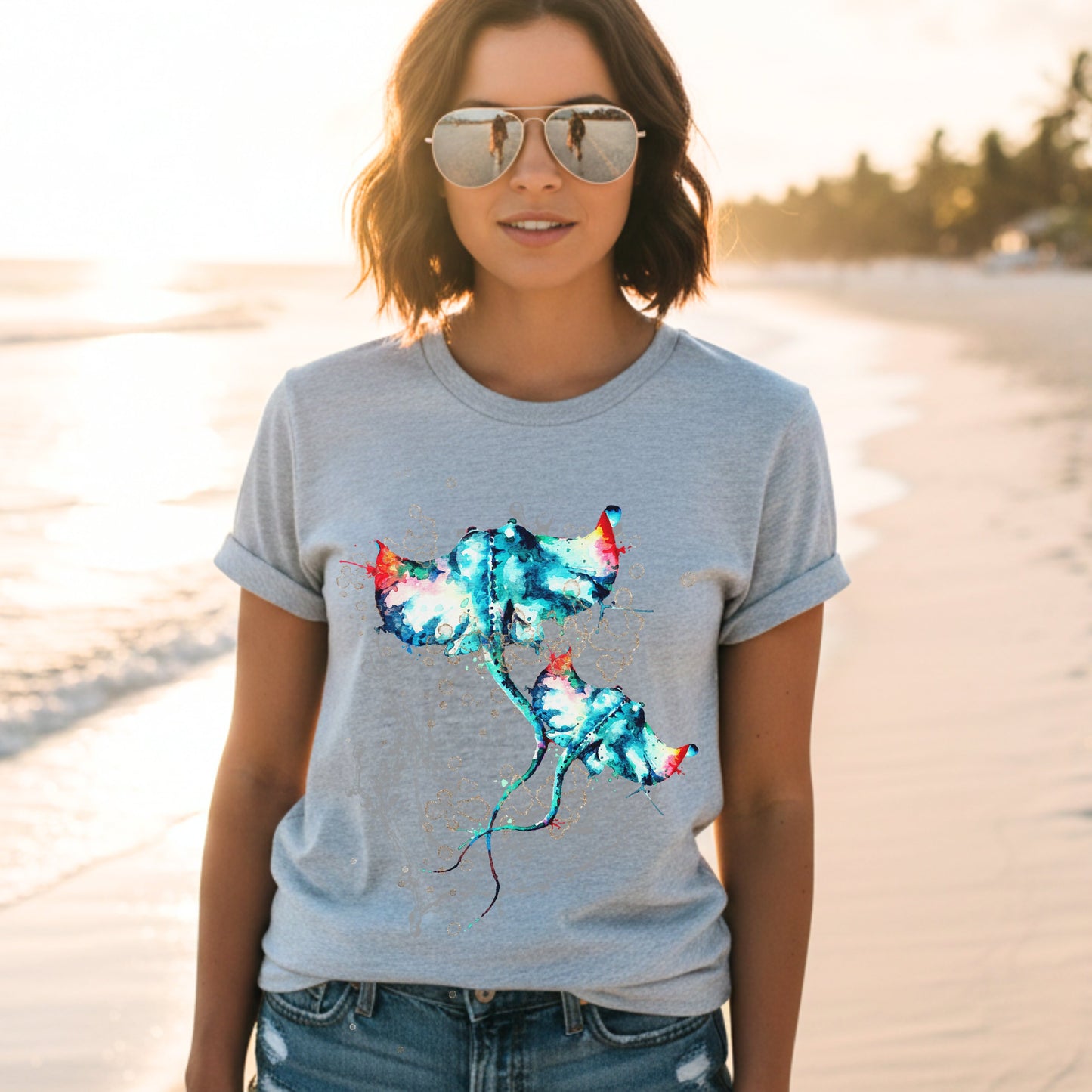 Woman wearing an athletic heather t-shirt with a colorful stingray design on a beach.