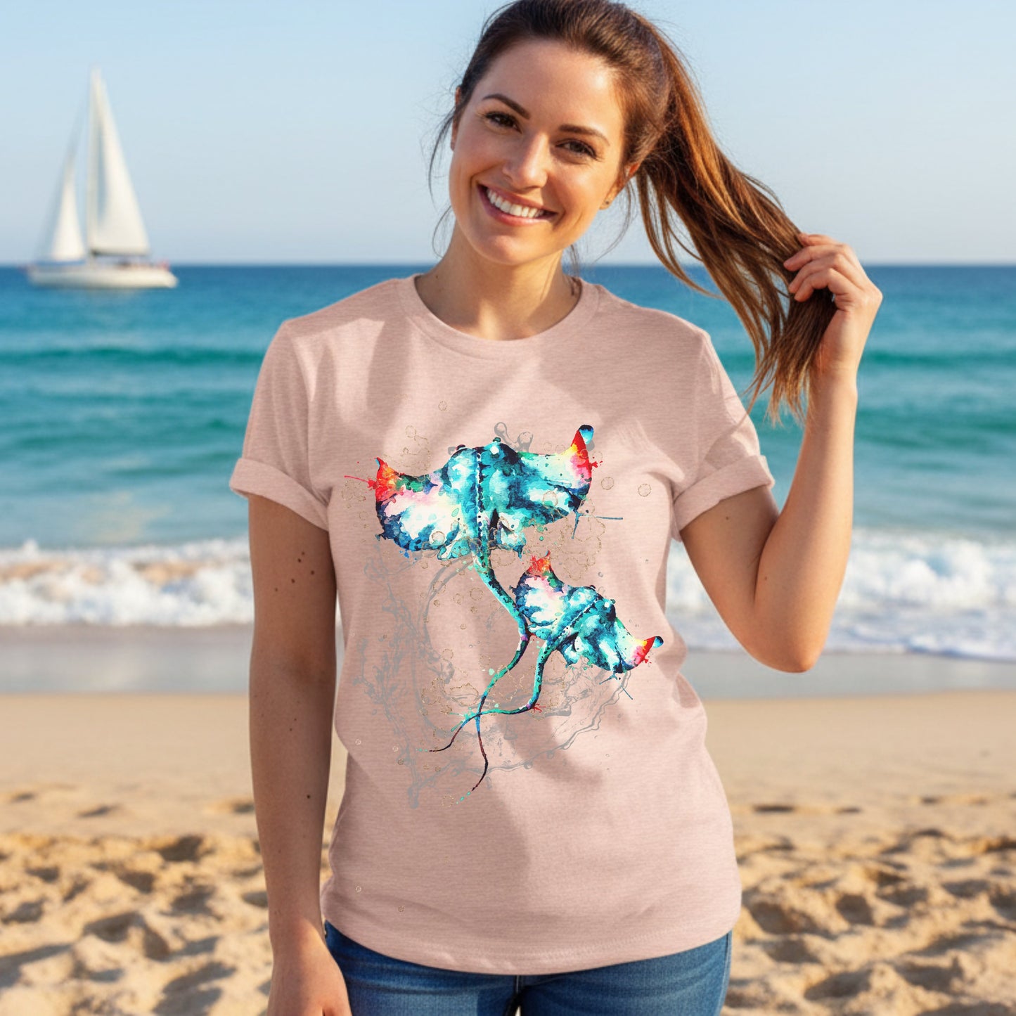 Woman wearing a heather peach t-shirt with a stingday design on a beach