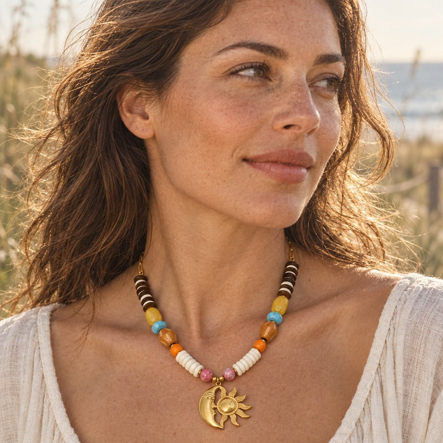Woman in a cream linen top wearing a gold sun and moon beaded necklace on a sunlit beach path