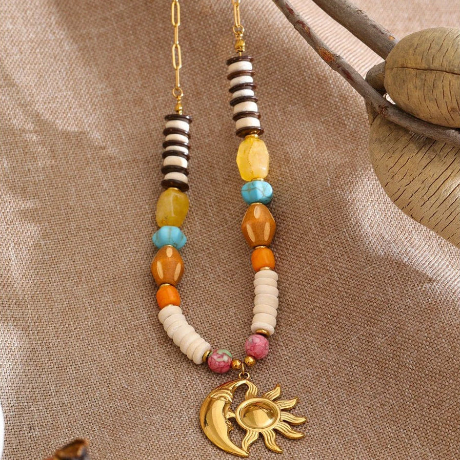 Sun and moon beaded necklace laid on natural linen beside a dried seed pod