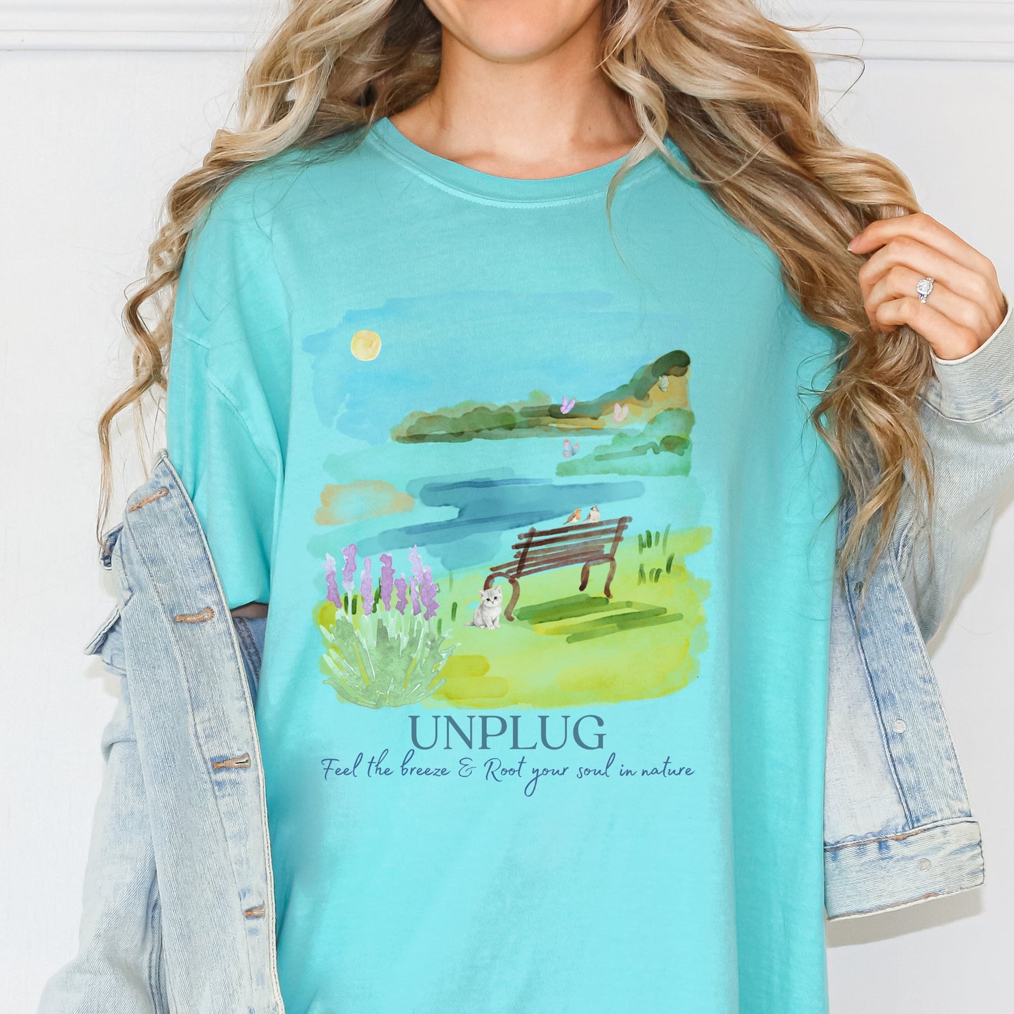 Woman wearing a Comfort Colors chalky mint color t-shirt with a nature graphic and 'UNPLUG' text by Crossroads Dandelion