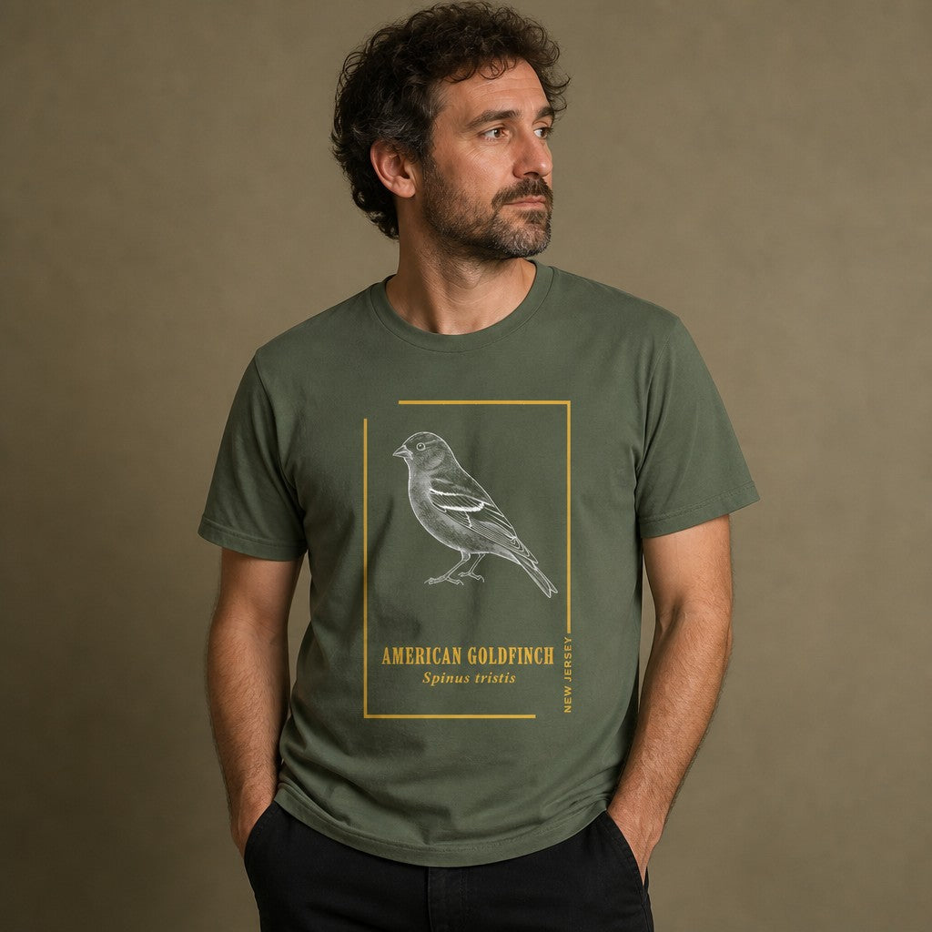 Man wearing a military green Bella Canvas 3001 t-shirt featuring a vintage etching of an American Goldfinch in a golden frame with elegant serif lettering, classic field guide style, for birdwatchers and wildlife art lovers, by Crossroads Dandelion