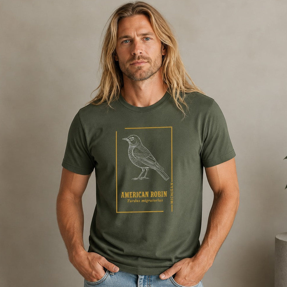 Man wearing a military green Bella Canvas 3001 t-shirt featuring an intricate white linework American robin illustration in vintage field-guide style with minimalist gold border and classic typography, ideal for birdwatchers and cottagecore enthusiasts, by Crossroads Dandelion