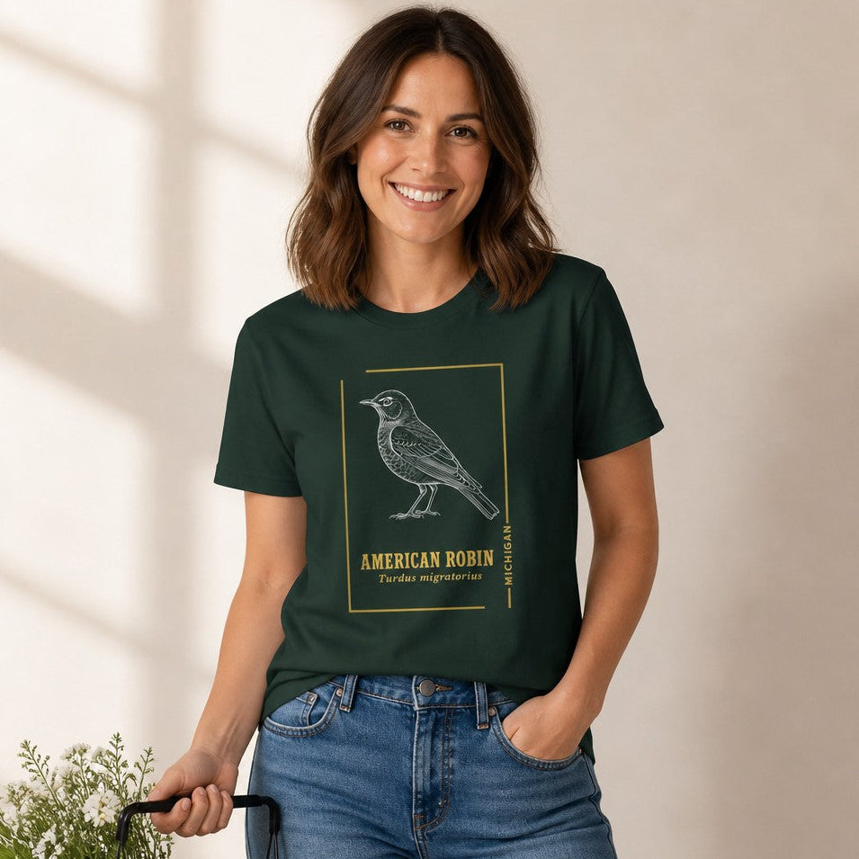 Woman wearing a Bella Canvas 3001 t-shirt in forest green with a vintage-style white line art illustration of an American robin, minimalist gold border, and elegant typography, inspired by classic nature guides, perfect for birdwatchers, naturalists, and cottagecore enthusiasts, by Crossroads Dandelion