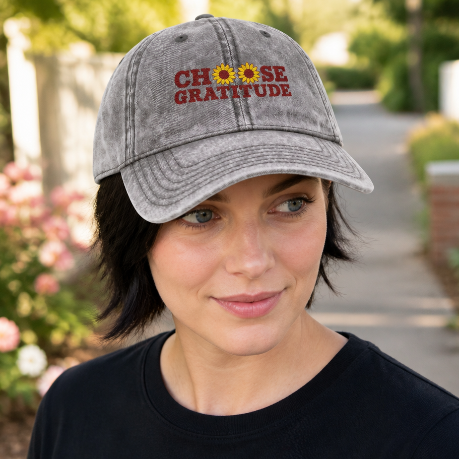 Woman wearing a charcoal grey vintage baseball cap featuring a 'Choose Gratitude' text with sunflower accents, casual outdoor setting, perfect for women who appreciate positive messages and floral designs, by Crossroads Dandelion