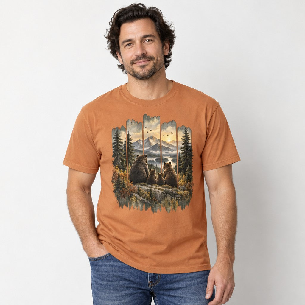 Man in yam orange Comfort Colors® 1717 t-shirt with a vintage-style painted scene of a brown bear family on a rocky ledge gazing at snow-capped mountains, golden sunset, winding river, framed by evergreen pines and autumn foliage in a rustic wood-panel design, perfect for hikers, campers, and wildlife lovers, by Crossroads Dandelion
