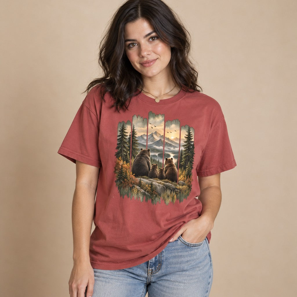 Woman in crimson Comfort Colors® 1717 t-shirt featuring a vintage painted bear family gazing at snow-capped mountains and sunset, rustic cabin art with distressed wood frame, perfect for hikers, campers, and nature lovers, by Crossroads Dandelion