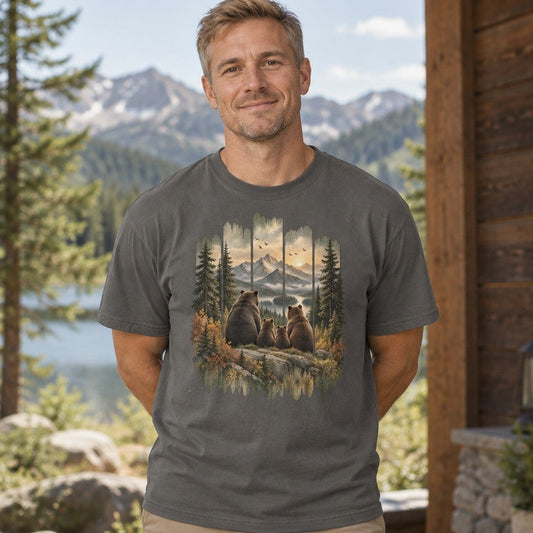 Man wearing a pepper Comfort Colors® 1717 t-shirt featuring a vintage-style painted scene of a brown bear family gazing over snow-capped mountains, sunset sky, and pines, rustic woodland design, perfect for hiking, camping, and wildlife lovers, by Crossroads Dandelion