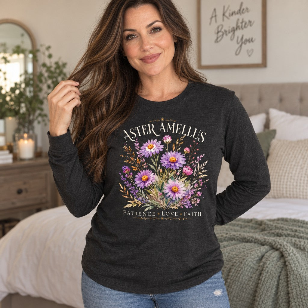 Woman wearing a dark grey heather Bella Canvas® 3501 long sleeve shirt featuring a vintage botanical aster and amellus flower bouquet with golden wheat and cream serif text, romantic cottagecore style, cozy bedroom setting, nature-inspired apparel for women who love floral and inspirational designs, by Crossroads Dandelion