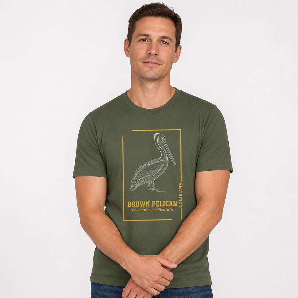 Man wearing a Bella Canvas 3001 military green t-shirt with a vintage engraved brown pelican illustration framed in golden ochre lines, classic wildlife design for birdwatchers and nature lovers, by Crossroads Dandelion