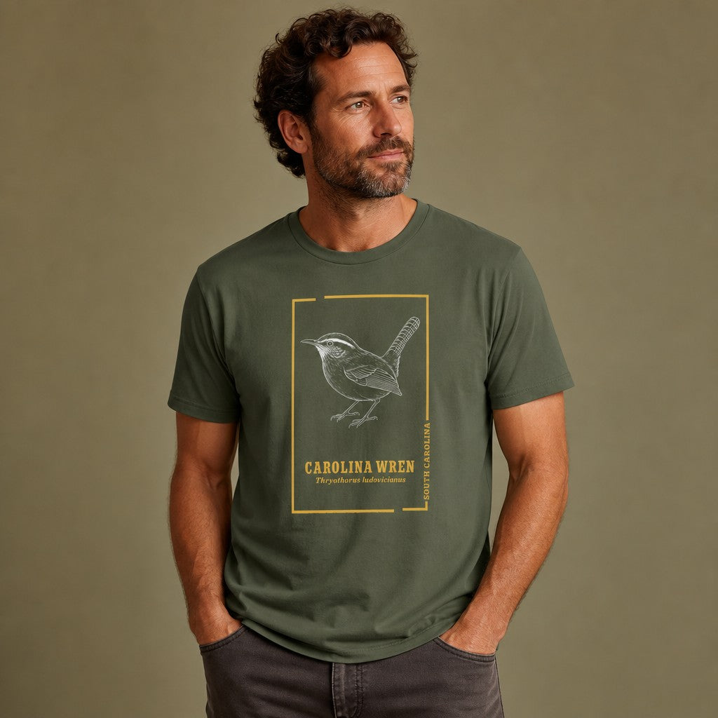Man wearing a military green Bella Canvas 3001 t-shirt featuring a vintage hand-drawn Carolina Wren within a golden frame, cottagecore aesthetic, perfect for bird lovers and nature enthusiasts, by Crossroads Dandelion