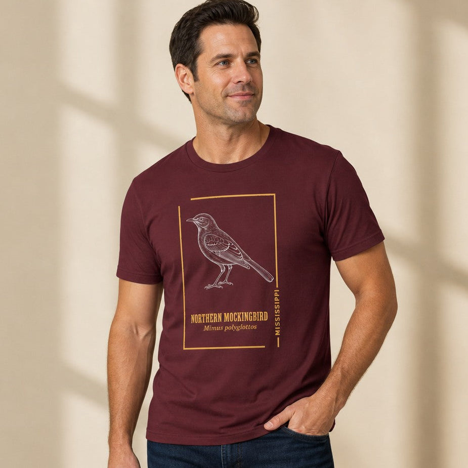 Man wearing a maroon Bella Canvas 3001 t-shirt featuring a vintage hand-sketched Northern Mockingbird illustration with gold framing, perfect for classic wildlife and birdwatching enthusiasts, by Crossroads Dandelion